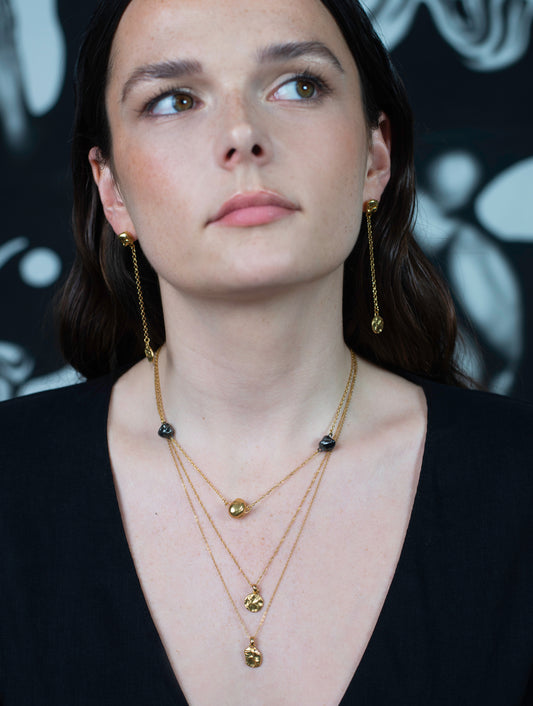 Model wearing layered gold Richard Murphy necklaces