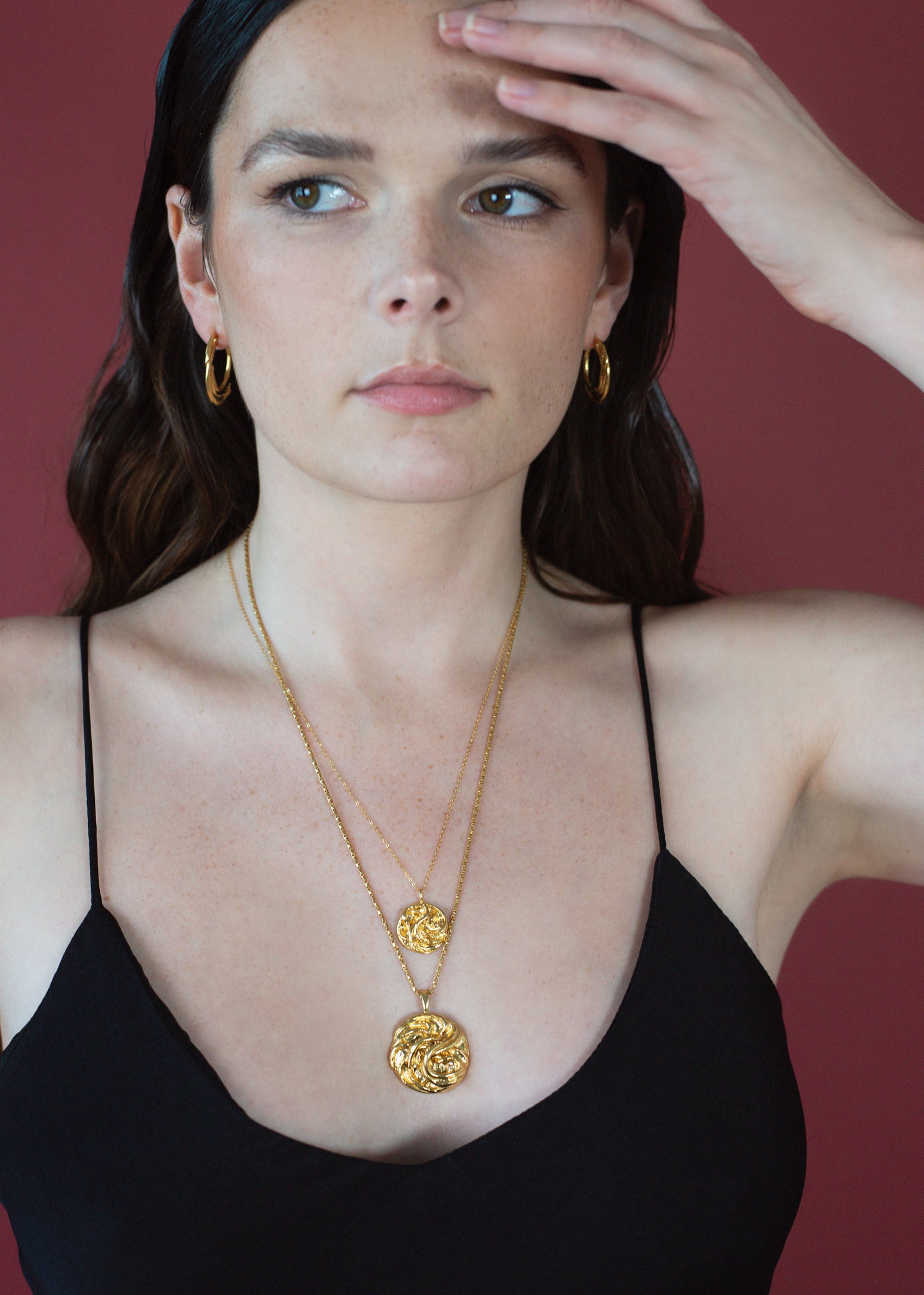 Model wearing hoops with triskele design necklace