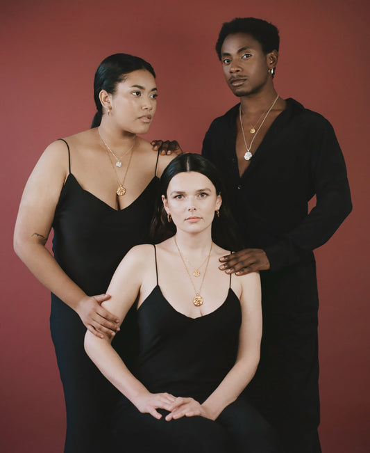 3 models wearing black silk clothing with layered gold and sterling silver necklaces