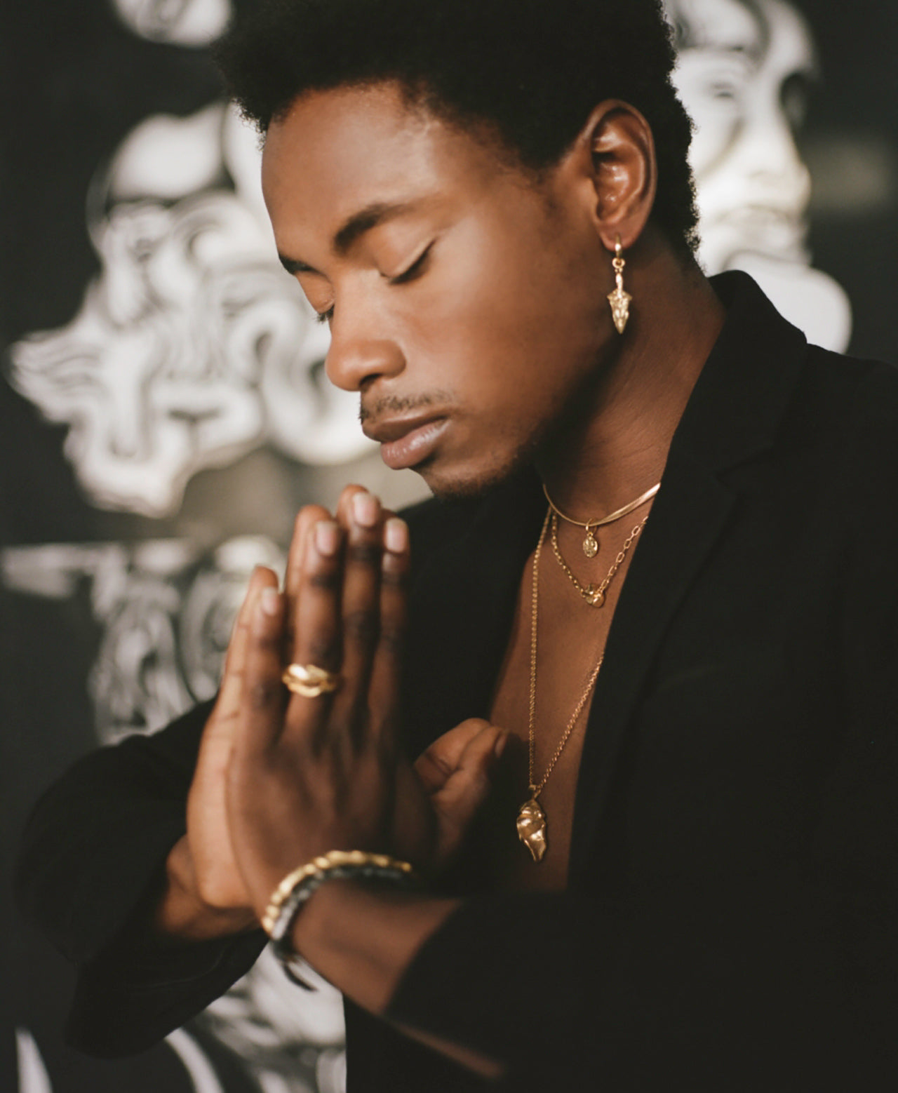 Model wearing spear shaped earring with layered necklaces