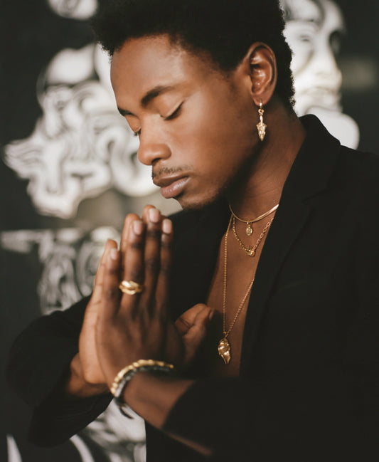 Model wearing spear shaped earring with layered necklaces