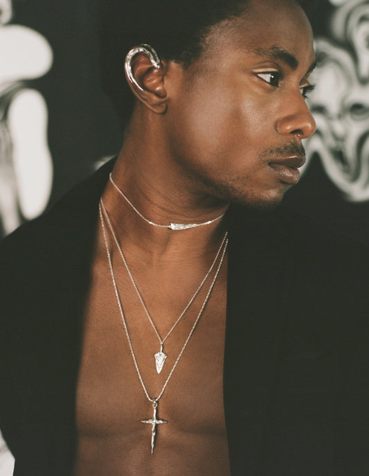 Model wearing sterling silver spear shaped necklace with crucifix necklace