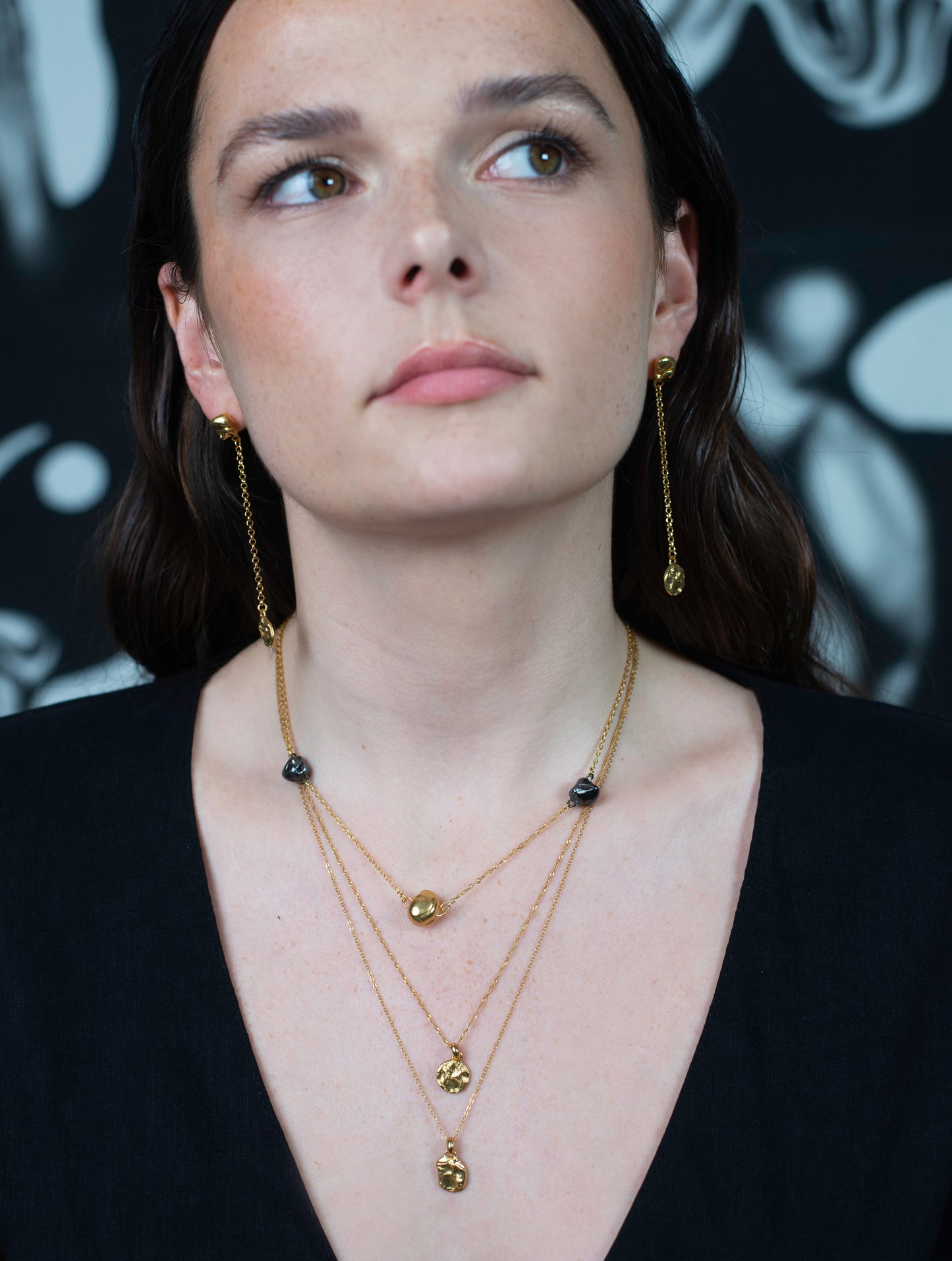 Model wearing drop earrings with layered necklaces