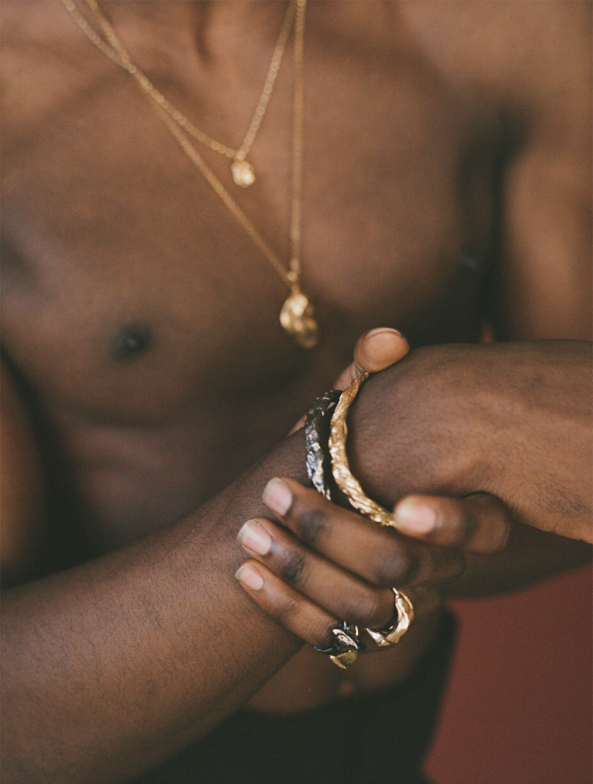 Model wearing black and gold bangles with chunky rings