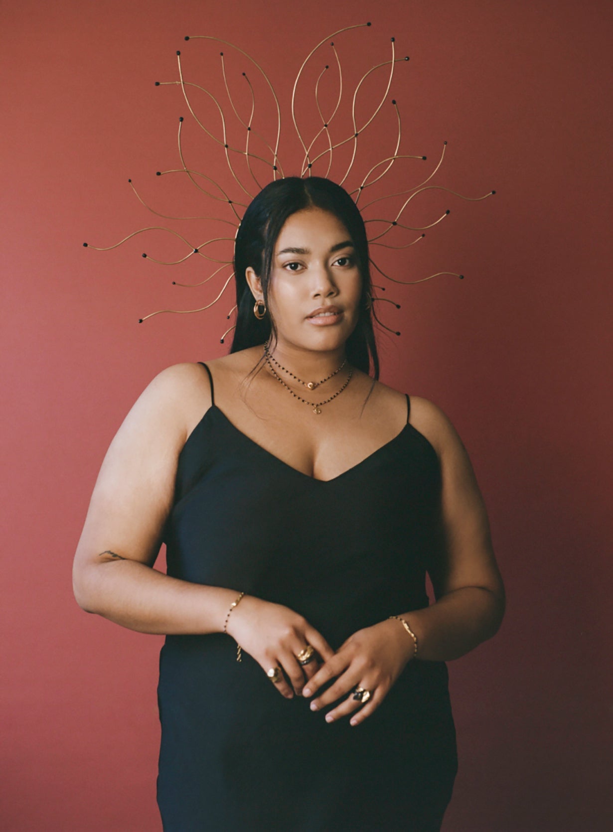 Model wearing gold vermeil bracelets, headpiece and rings with red background