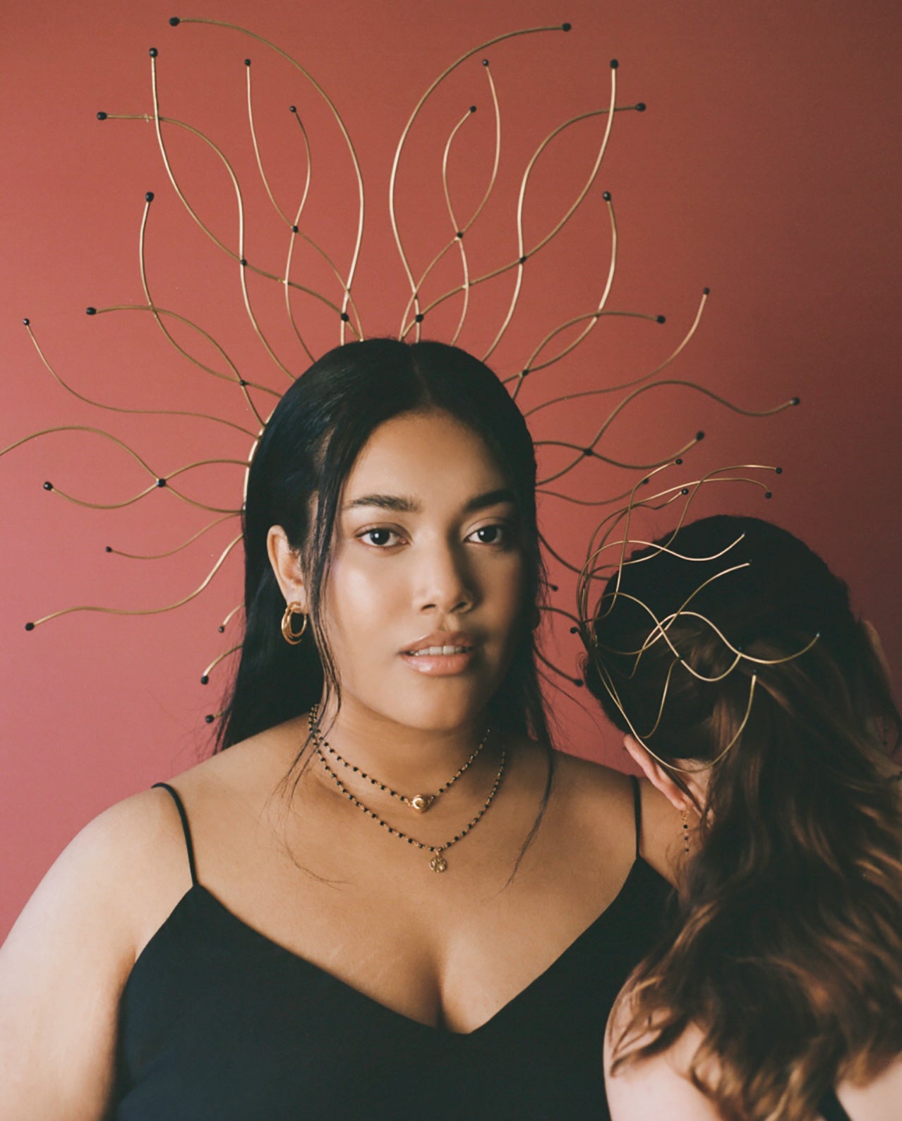 Model wearing gold headpiece, earrings with black beaded chain and slip dress