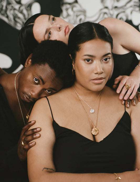 3 models posing wearing large pendant necklaces