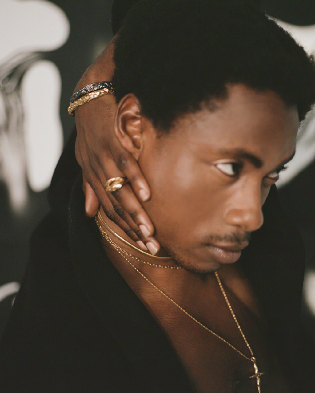 Model wearing crucifix necklace with gold ring and bracelets