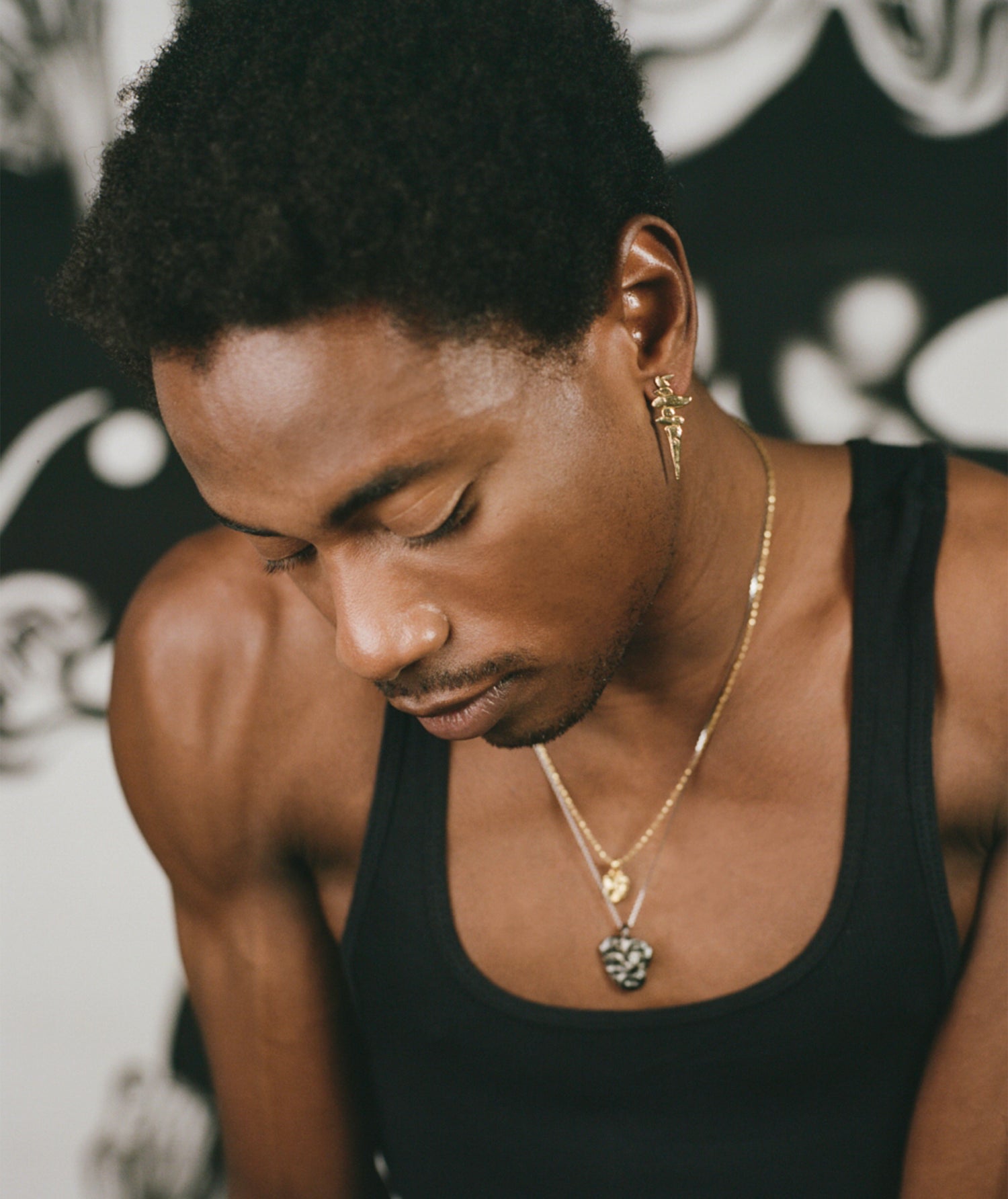 Model wearing gold earring with layered handcrafted necklaces