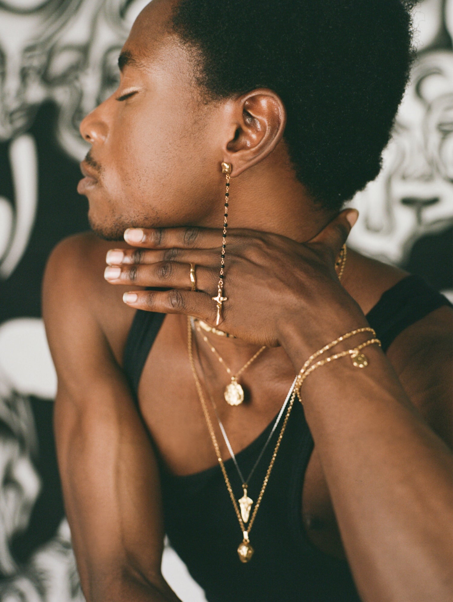 Model wearing layered necklaces, gold bracelet and crucifix earring